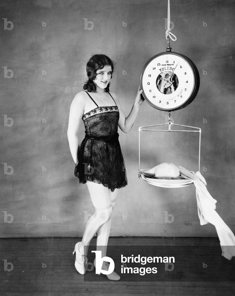 Portrait of a Young Woman Weighing her Clothes on a Weighing Scale
