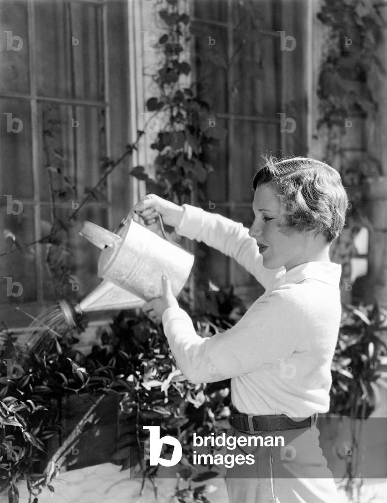 Woman Watering Plants in Window Boxes