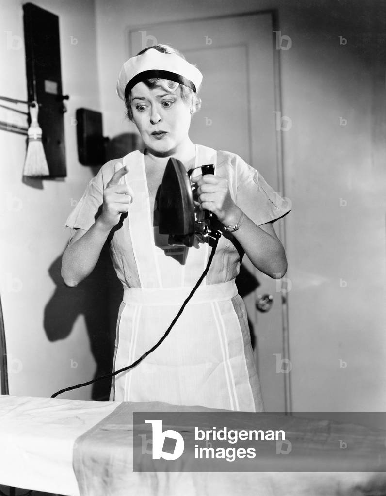 Young Woman with Iron in her Hands Testing it if it is Hot