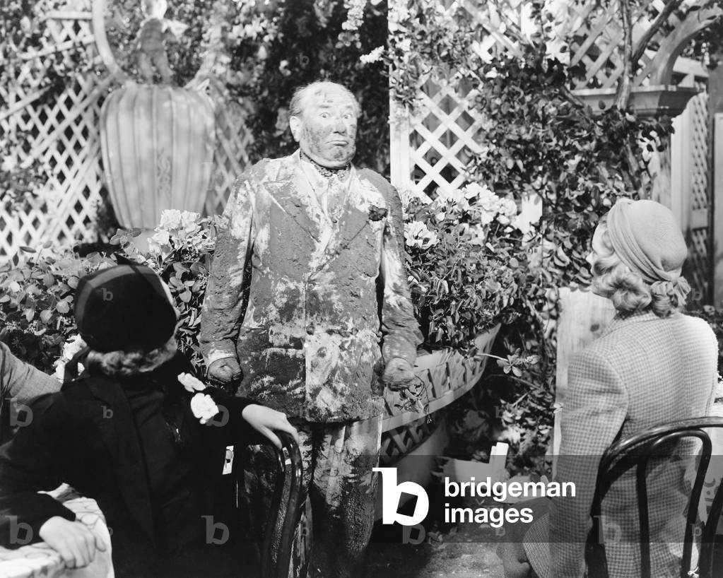 Man Covered in Mud Standing in Front of Two Ladies