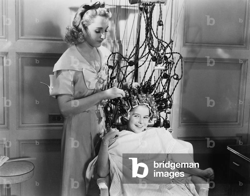 Woman Using Machine to Style Teenage Girls Hair