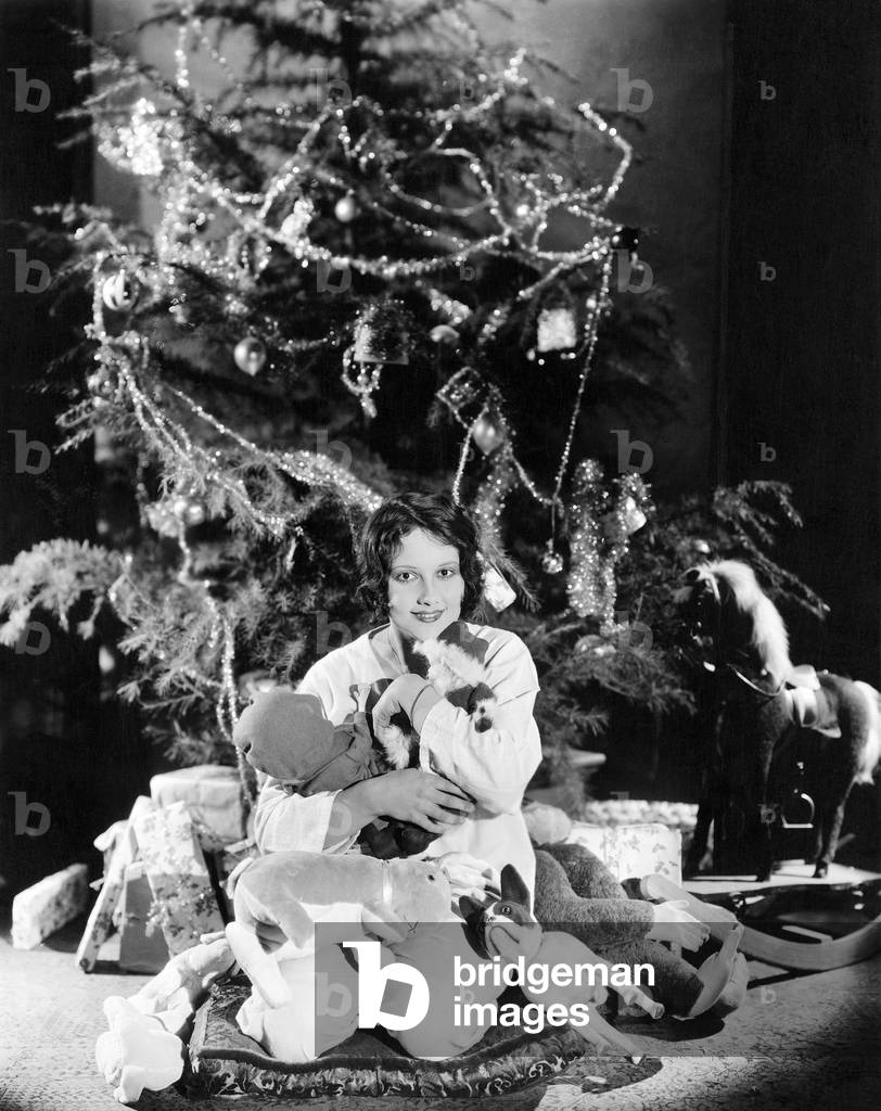 Teenage Girl Hugging Stuffed Animals Under Christmas Tree