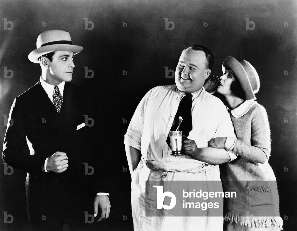 Young Man Upset with a Waiter While a Woman is Whispering Into the Waiters Ear