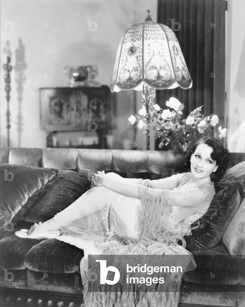 Woman Wrapping her Hands Around her Knees Nestled on a Couch