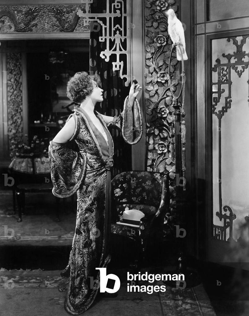 Young Woman Standing and Talking to her Parrot