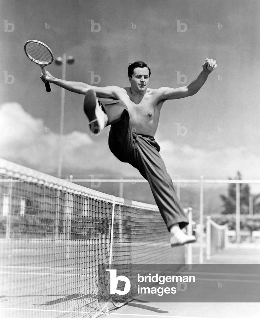 Male Tennis Player Jumping Over Net