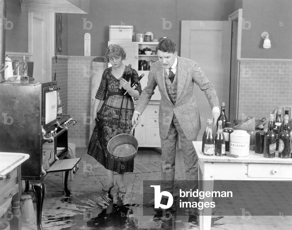 Man and woman looking at spilled liquid on kitchen floor