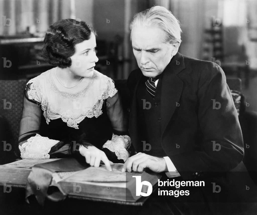 Couple Sitting Together and Looking at a Book with a Worried Facial Expression