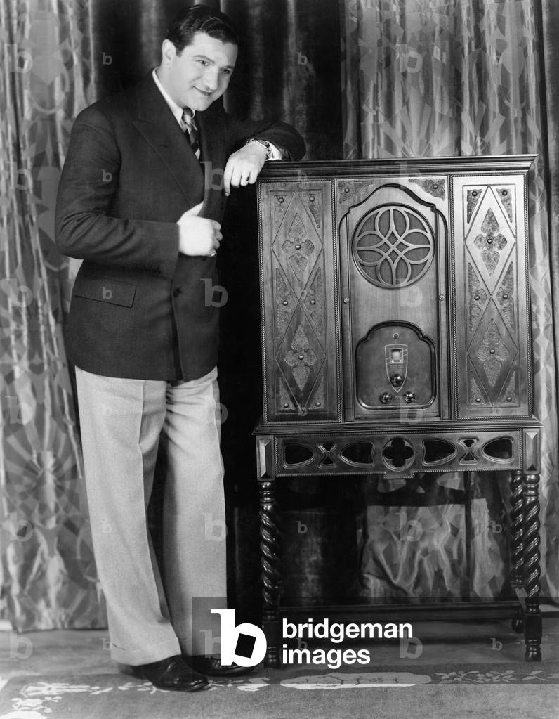 Young man standing near a radio and smiling (EV005596_H)