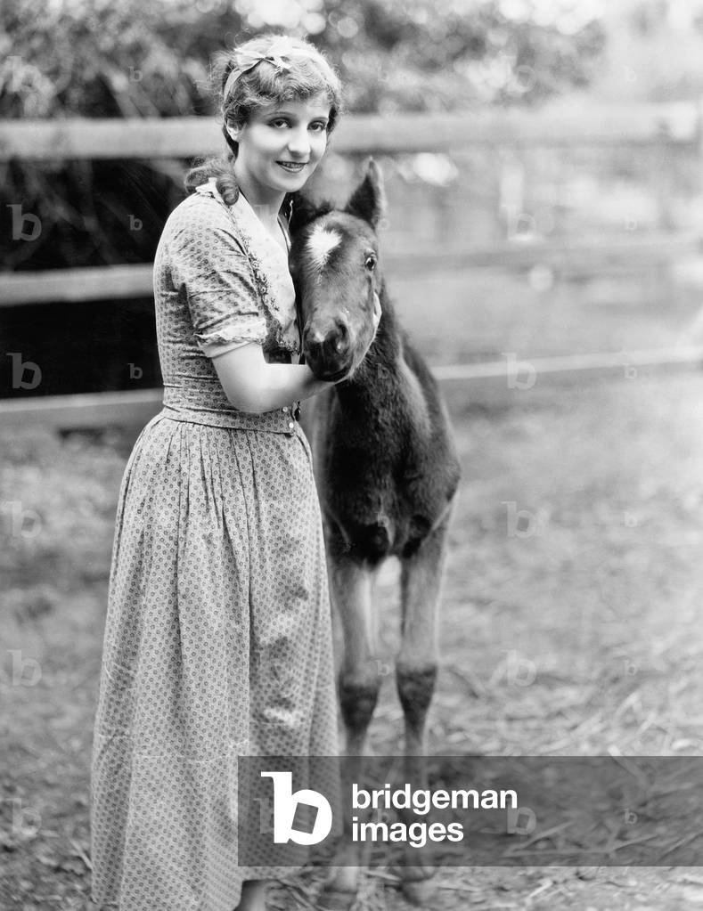 Woman Standing Next to a PoNY in a Corral