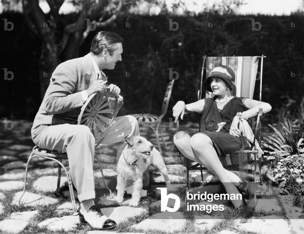 Couple Sitting in the Back Yard Talking with a Dog Between Them