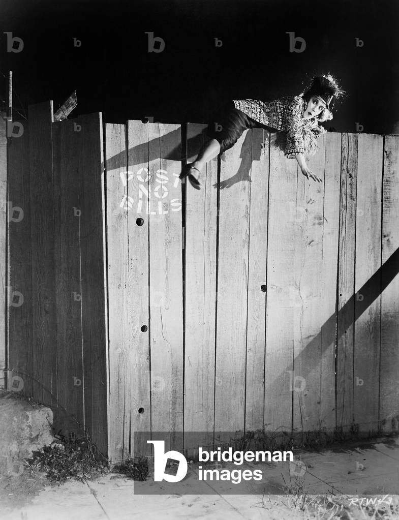 Young Woman Trying to Climb Over a Wooden Fence