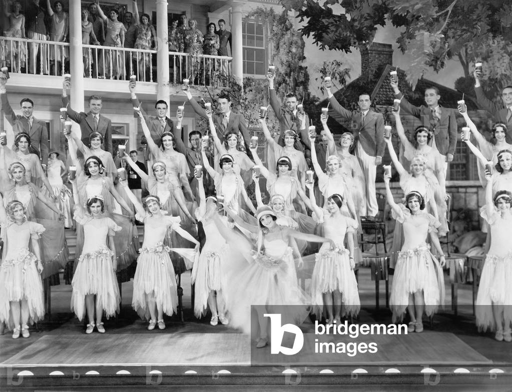 Group of Dancers Standing on a Stage with Their Arms in the Air and a Drink in Their Hands