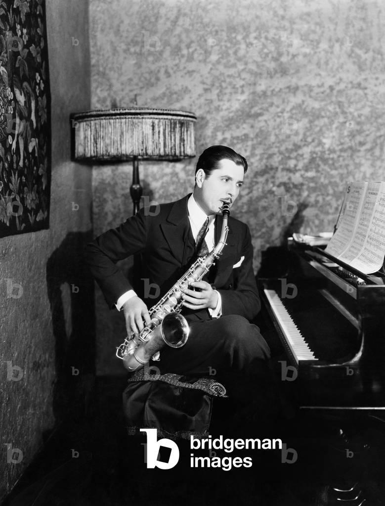 Man Sitting at Piano Playing Saxophone