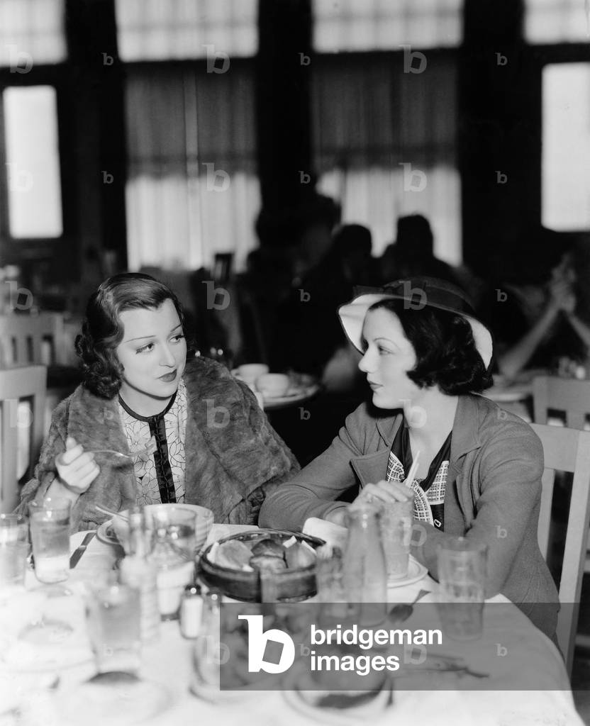 Two Young Women Sitting in a Restaurant and Looking at Each Other