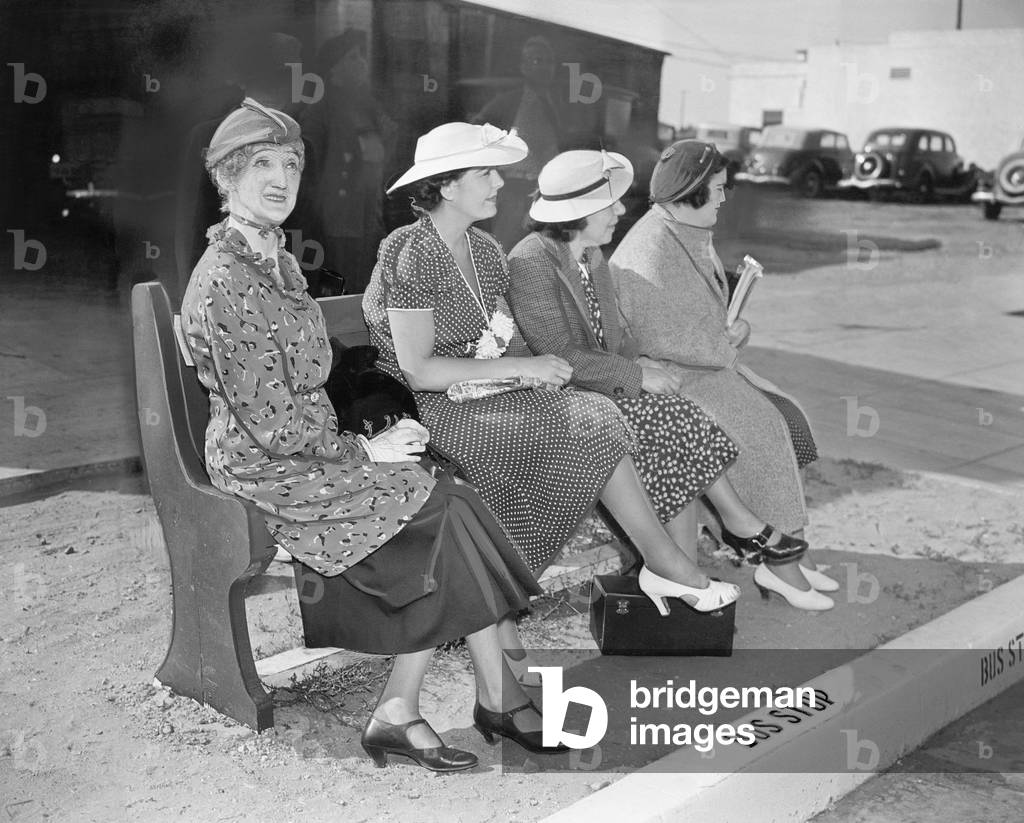 Four Women Sitting on a Bench Waiting for the Bus