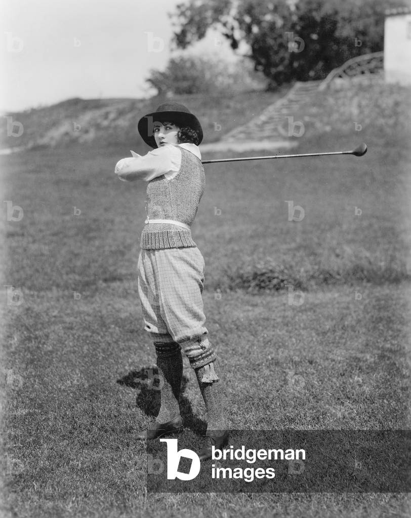 Young Woman Swinging a Golf Club on a Golf Course