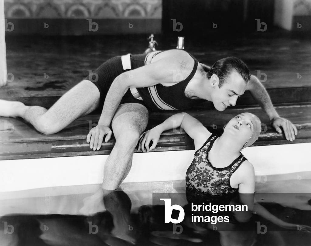 Man Bending Over to Kiss a Woman in a Swimming Pool