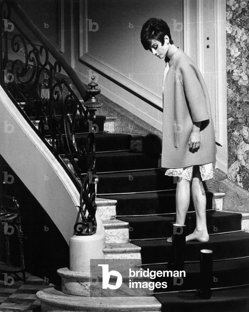 Audrey Hepburn is going up on the stairs of a luxurious house, naked feet