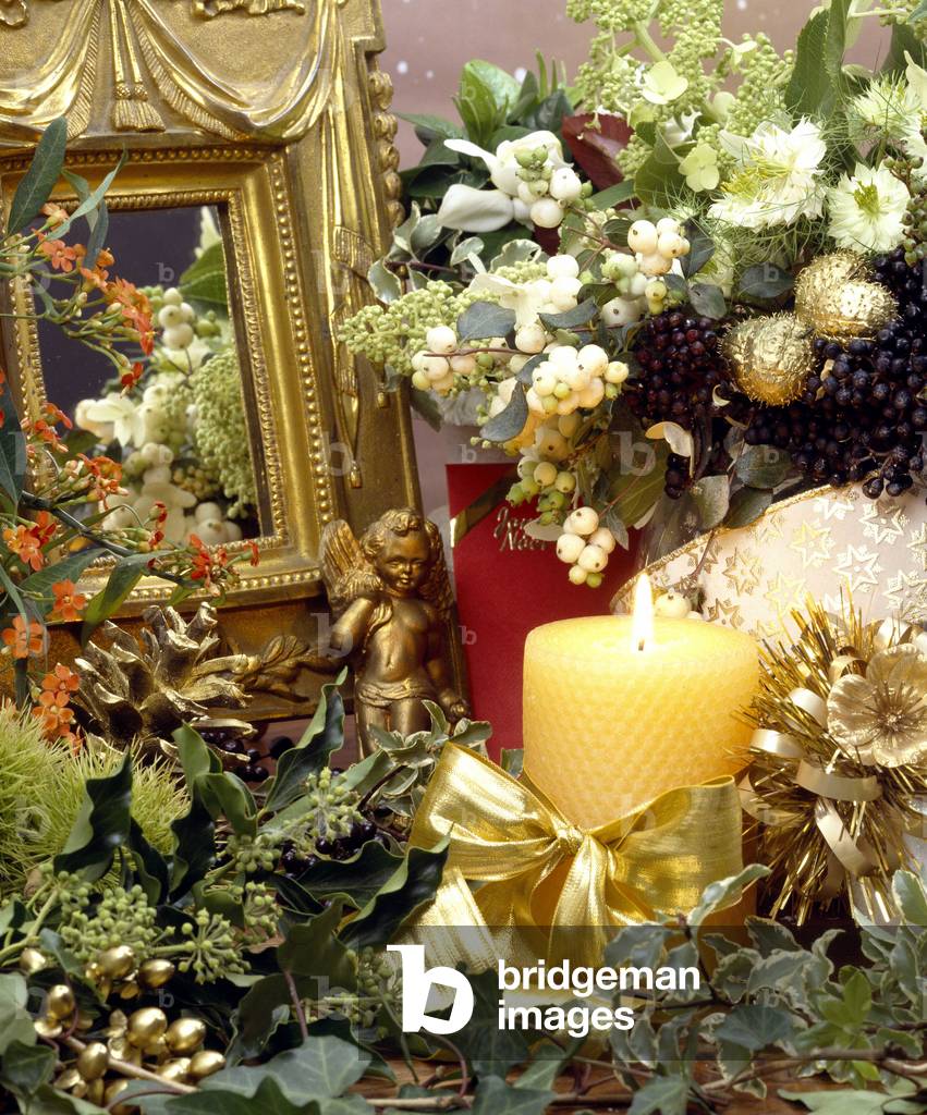 Still life of a Christmas composition with a candle and a dore angel. A table appears in the background.