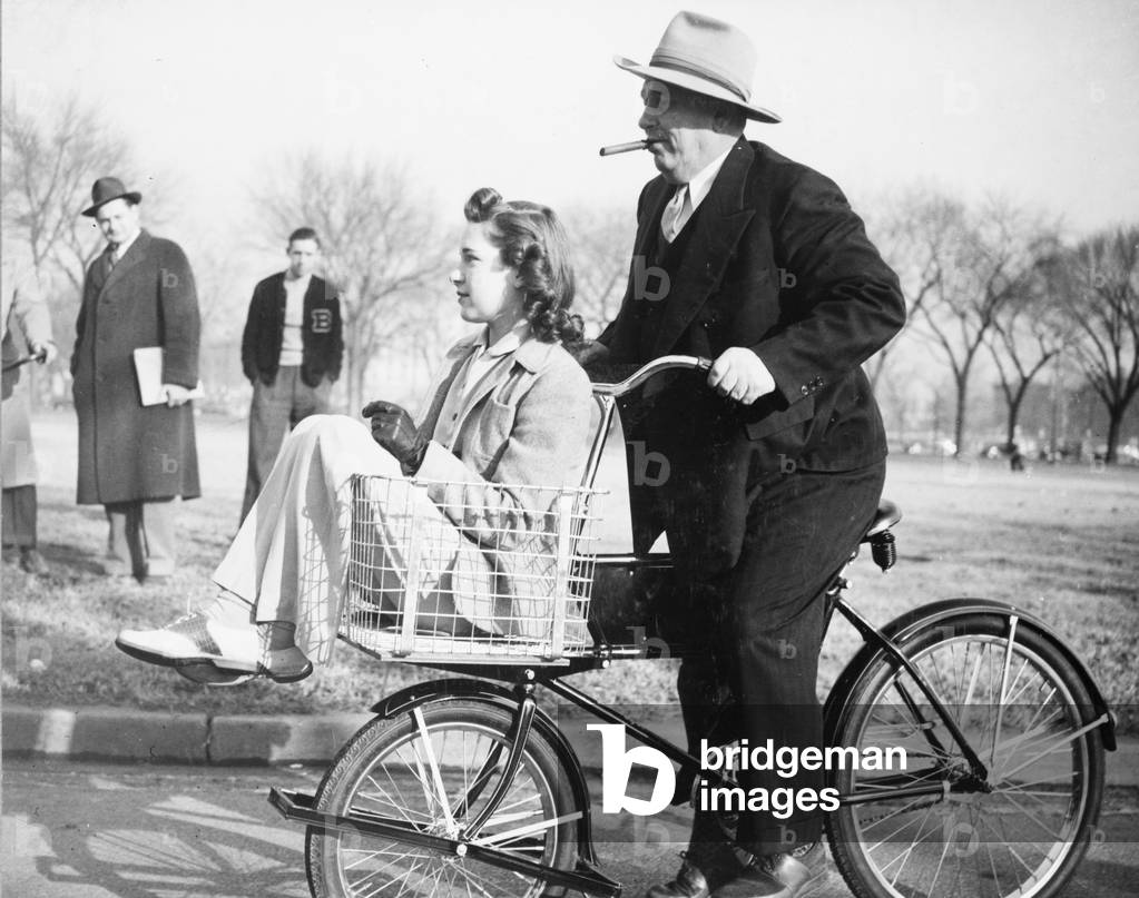 Miss Betty Barrett, an OPM stenographer, in the parcel basket of a 'Victory' bicycle, 1942 (b/w photo)