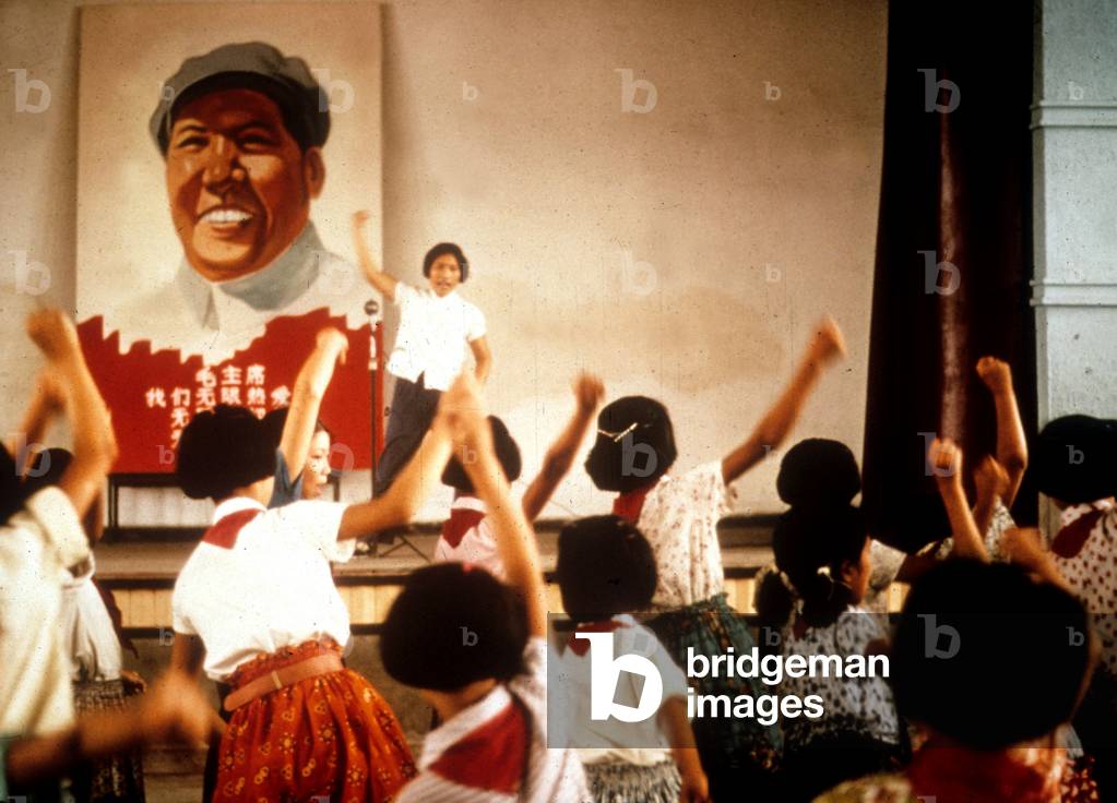 In A School in China : Political Education : Children, With Red Scarf, Rauising Fist in Front of The Protrait of Maozedong, 1973 (Cultural Revolution) (photo)