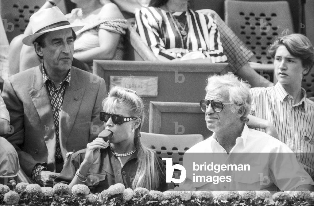 French actor Jean Paul Belmondo attending Roland Garros tennis tournament with his girlfriend Natty (Nathalie Tardivel) on May 31, 1991 (b/w photo)