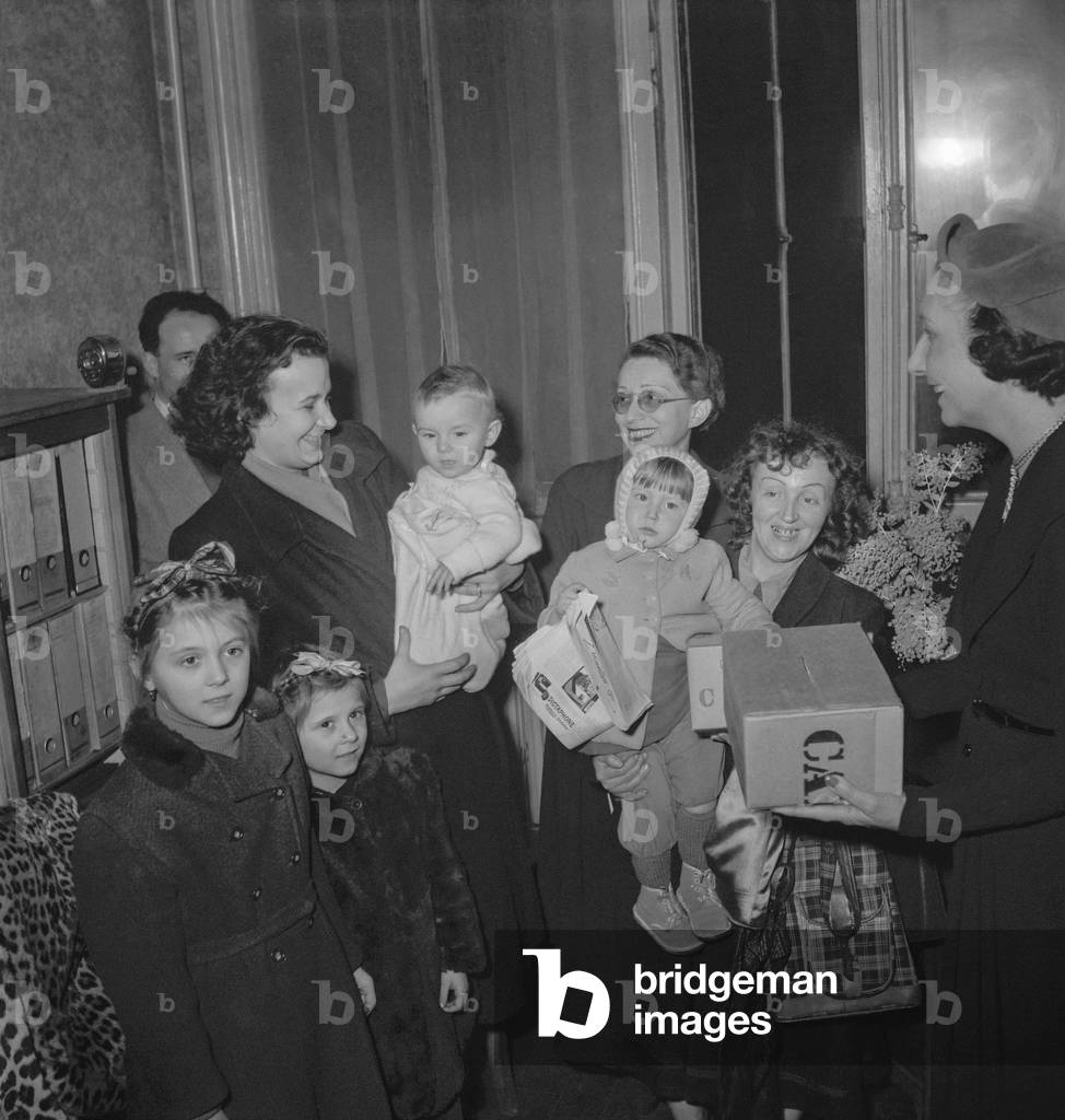 Mrs Vincent Auriol (Michelle Aucouturier) giving packets to refugees from Czechoslovakia, Poland, Hungary, in Paris December 20, 1949 (b/w photo)