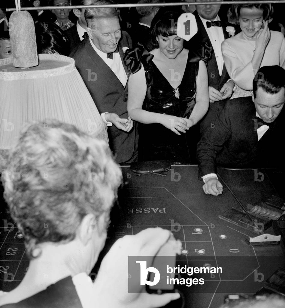 Gala of Charity Organized By Mauricechevalier at Maxim'S Restaurant in Paris January 27, 1965 : Regine (Regina Zylberberg) and Maurice Chevalier Playing Roulette (b/w photo)