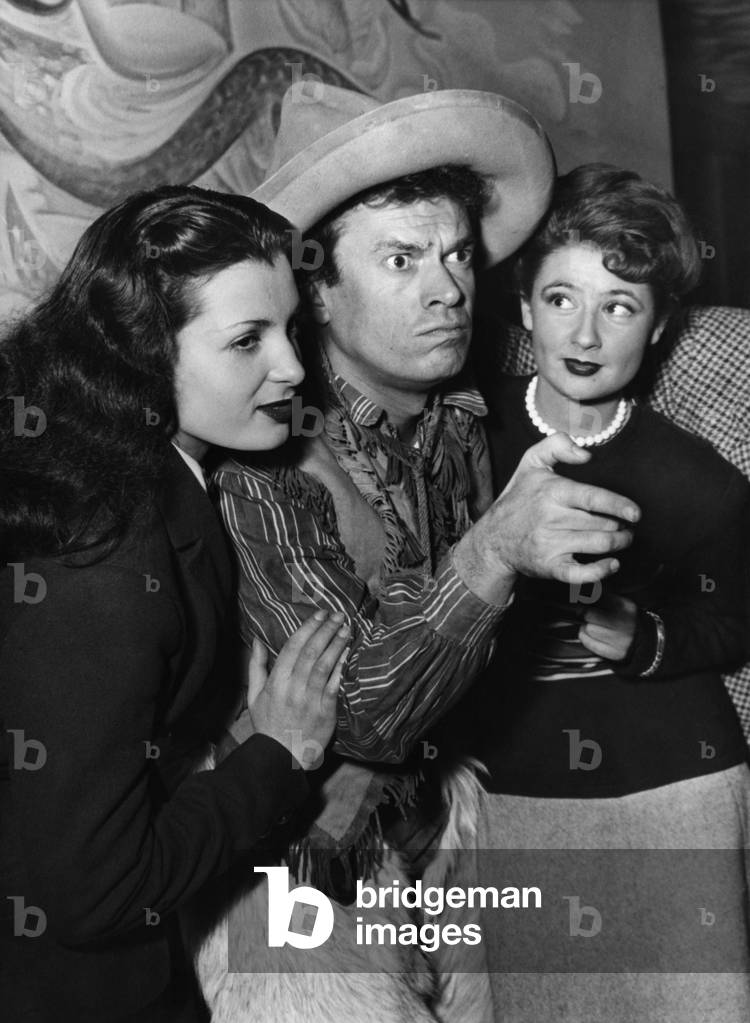 During a party at the Tavern of the Champs Elysees, Actor Pierre Dudan Under the Features of Buffalo Bill, which He plays in His Last Film Is In The Company Of Miss France (Left) And Miss Cannes. December 28, 1948 (b/w photo)