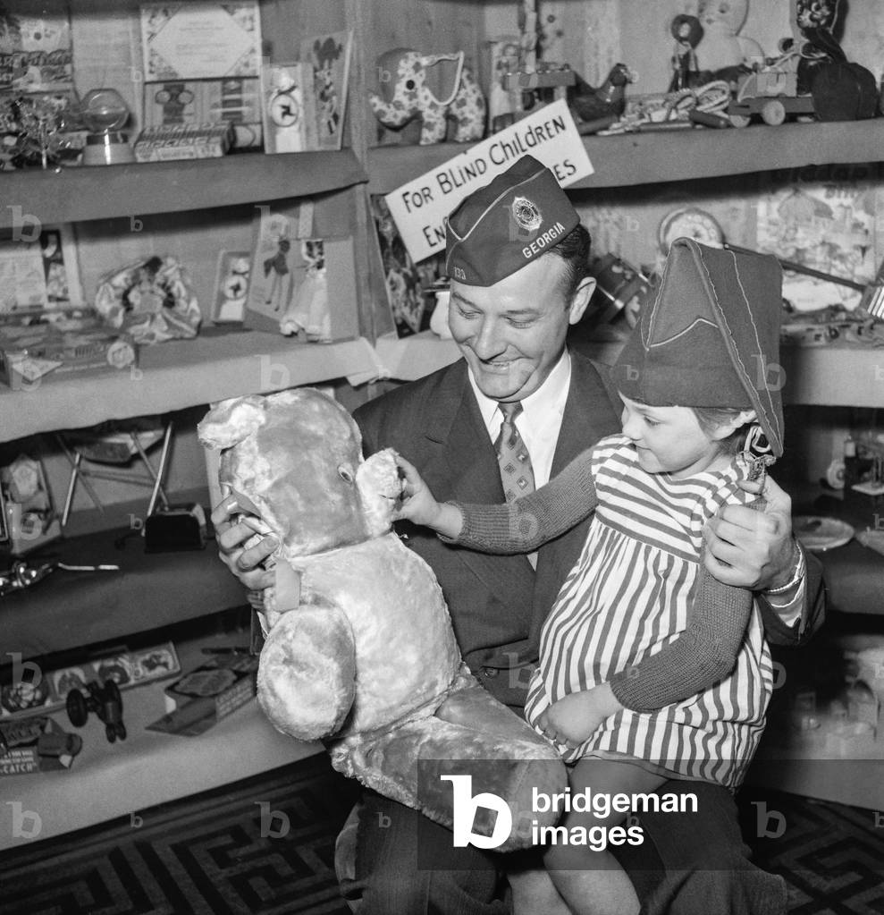 The American Legion is giving toys to European children who suffred from war, Paris, March 22, 1951 : here Erle Cocke Jr, member of the American Legion, giving a soft toy to a French girl (b/w photo)