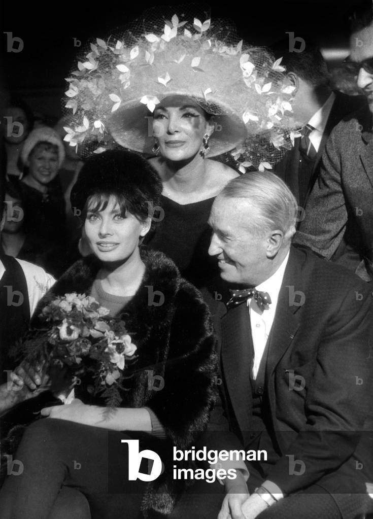 Sophia Loren, Maurice Chevalier and Model Lucie Daouphars, Called Lucky, With A Hat Full of Flowers By Parisian Couturier Jean Barthet on January 20, 1962 (b/w photo)