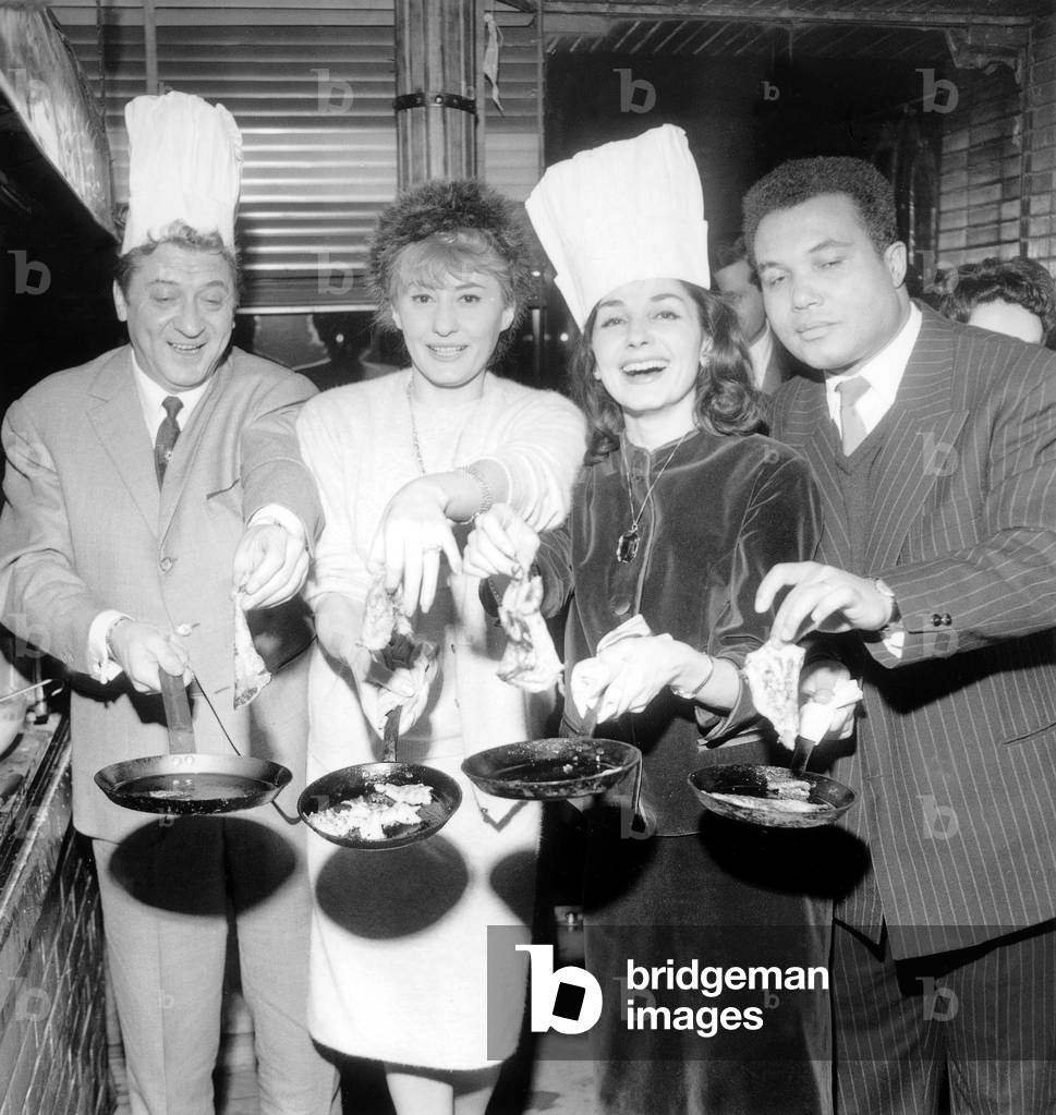 Roger Nicolas, Lucette Raillat, Maria Candido and John Williams Tossing Pancake For Candlemas February 2, 1961 (b/w photo)