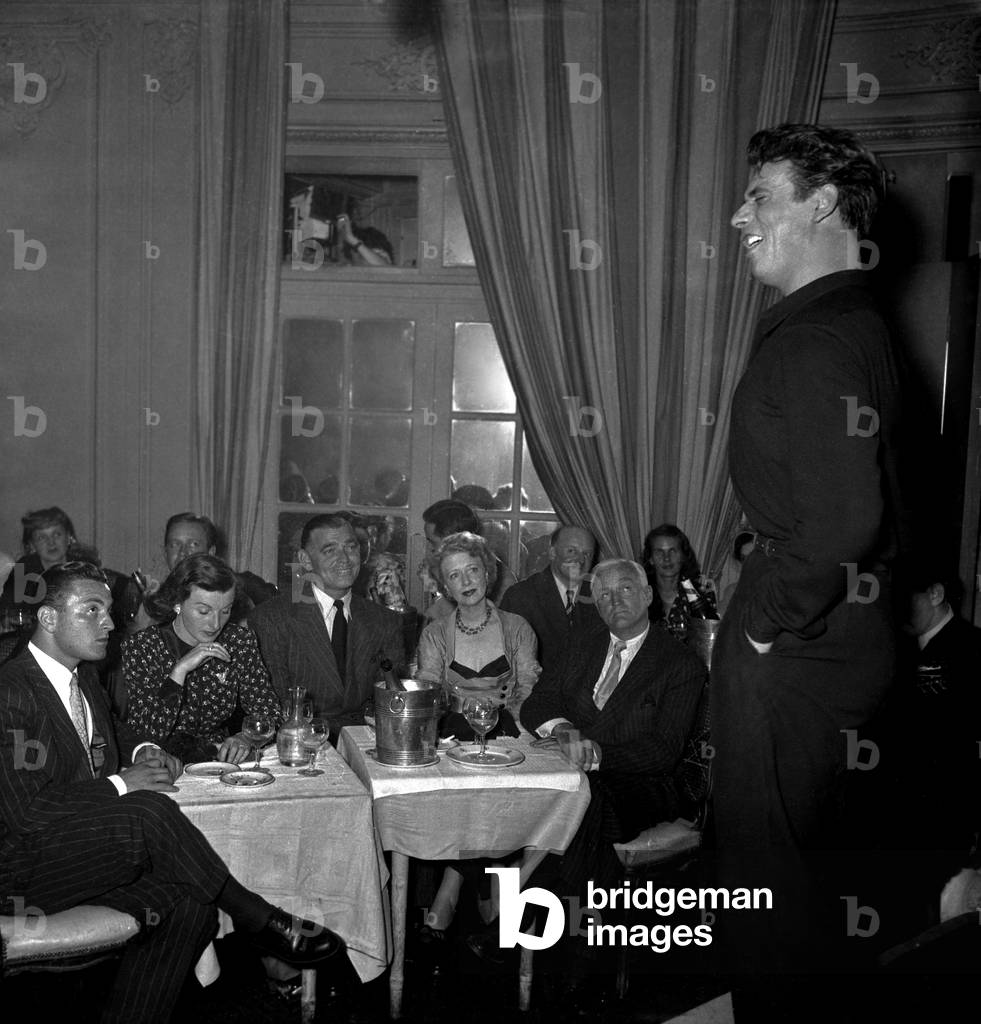 Yves Montand Singing in The Restaurant Cabaret Chez Carrere in Paris Under Look of Clark Gable and Mrs O'Brien, July 20, 1948 (b/w photo)
