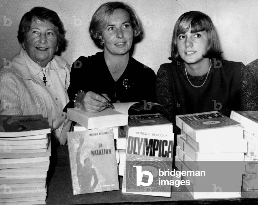 Right Christine Caron, Young Swimming Champion Coming to Assist Monique Berlioux At the Centre For Sale Her Two Books:” La Swimming” And “Olympica” Organized By La Maison Internationale Des Pen Clubs And By Le Pen Club Francais Au Plais Galliera In Paris, A Left Suzanne Berlioux, La Mere De Monique And L Coach Christine Caron November 28, 1964 (b/w photo)