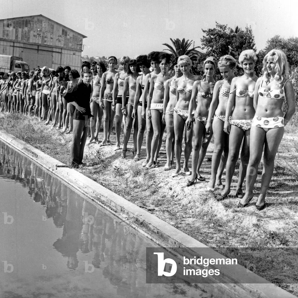 Candidates for the Contest: Miss Chance Blondo The Contest Presides By Lucky Blondo Reunites Young Women in the Near Nice (Cote D'Azur). La Laureate: Michele Bouler, Near Lucky Blondo With Black Briefs, White Belt, White Bra With Black Polka Dot On July 08 1964 (b/w photo)