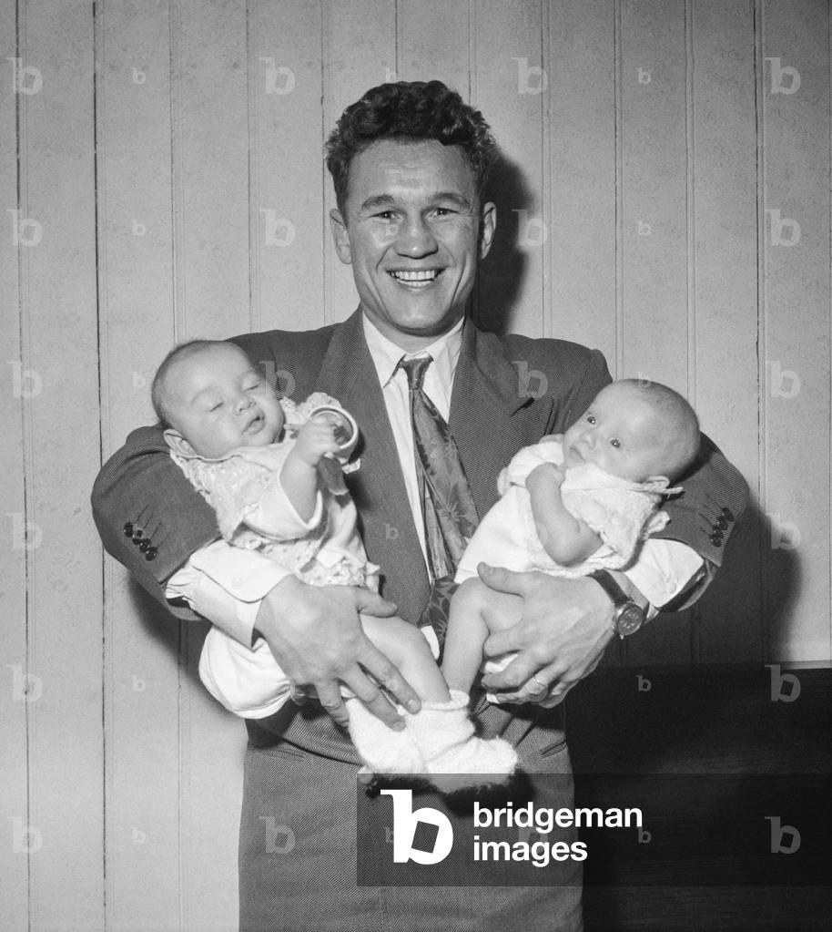 French boxer Laurent Dauthuille with his twins Laurent and Laurence at home in Buzenval, France, Janaury 27, 1951 (b/w photo)