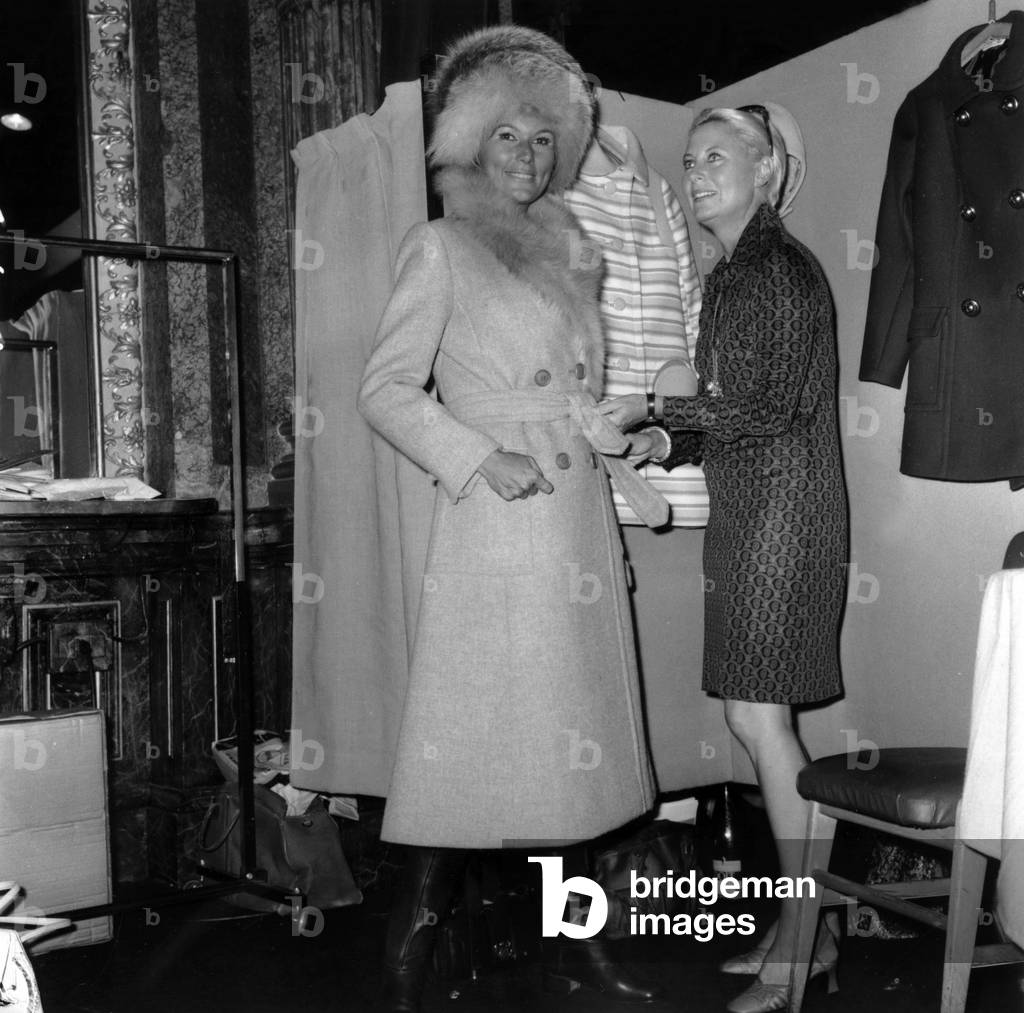 Michele Morgan Is Helping her Daughter-In-Law The Model Catherine Prou (Marshall) Who Is Showing A Coat With A Fur Collar and A Toque, Paris, September 8, 1969 (b/w photo)