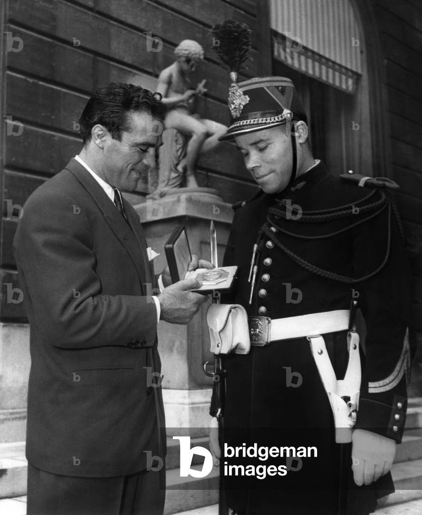 French Boxer Marcel Cerdan, New World Champion, Showing his Medal To A Guard on October 12, 1948 during A Recption at The Elysee Palace, Paris (b/w photo)