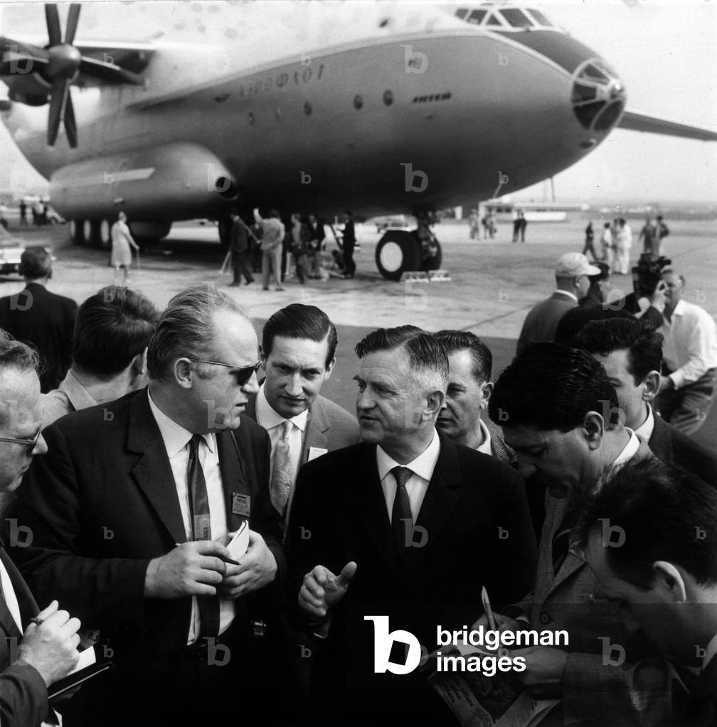 At the Salon du Bourget, in front of his Giant Aircraft “Antee” (The Largest Airplane in the World), his builder Antonov gives some explanations to journalists on June 15, 1965. (b/w photo)