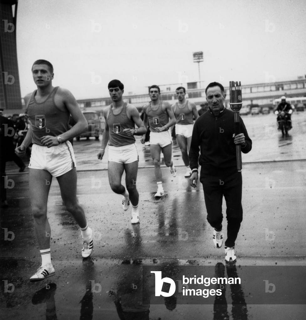 French Athlet Alain Mimoun Holding Olympic Flame (For Mexico Olympic Games) Between Orly Airport and Paris, December 19, 1967 (b/w photo)