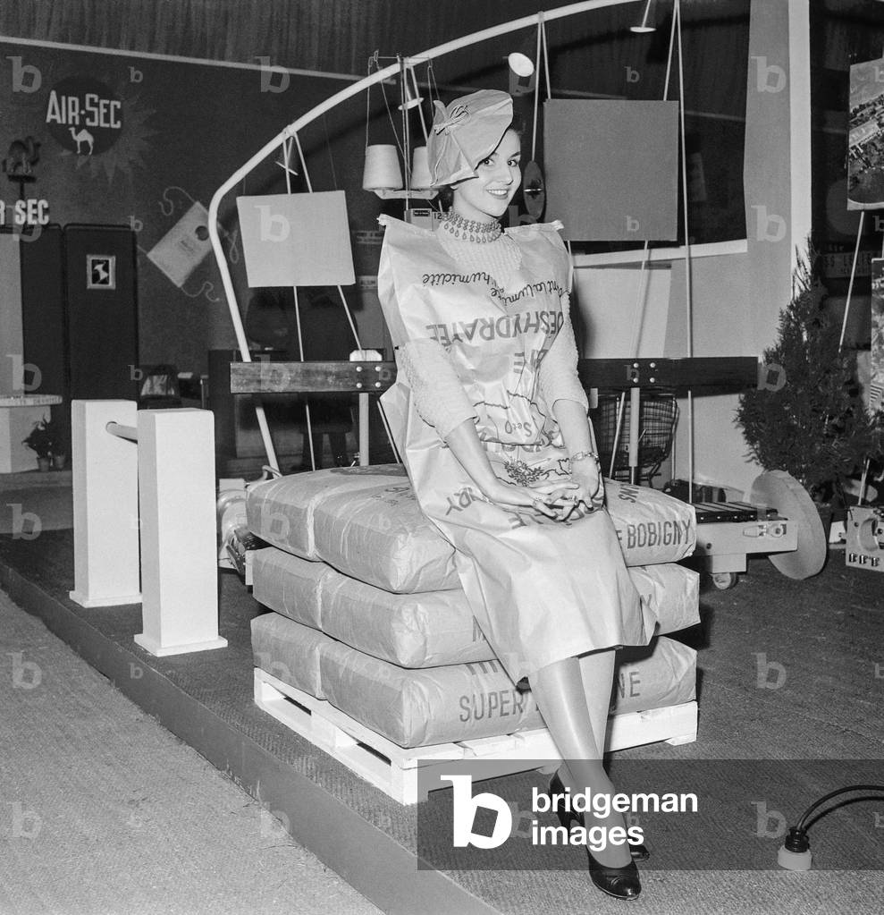 Wrapping show, Paris, October 31, 1956 : Monique Lambert, ex Miss France, wearing a suit made with wrapping paper (b/w photo)