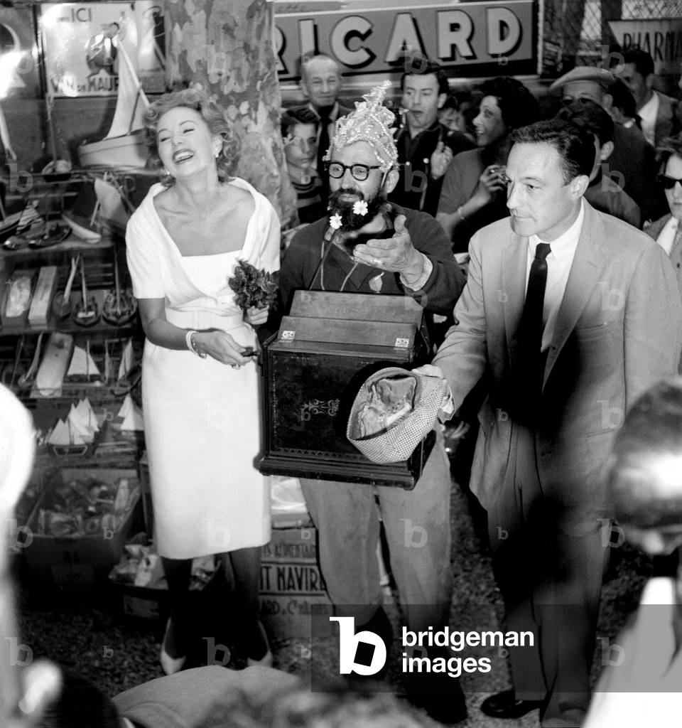 Ronda Fleming Playing Barrel Organ With Aguigui and Gene Kelly Passing The Hat Round at Cannes Film Festival May 4, 1959 (b/w photo)