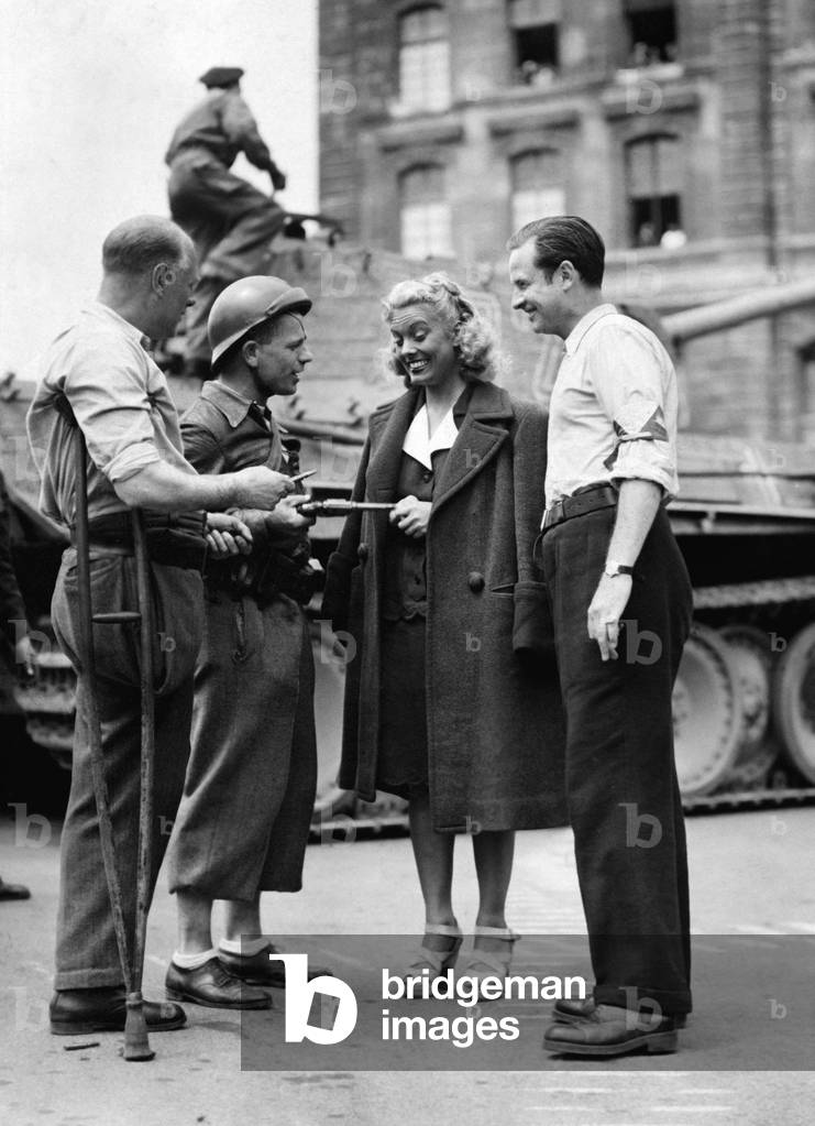 Reenactment of Scenes Of The Liberation Fighting Of Paris In Front Of The Police Prefecture On The Parvis Notre Dame For The Need Of The Film “A Flick” By Mauricedecanonge Here Suzy Carrier Featured Of The Movie Talking With Some Performers On June 16, 1947 (b/w photo)