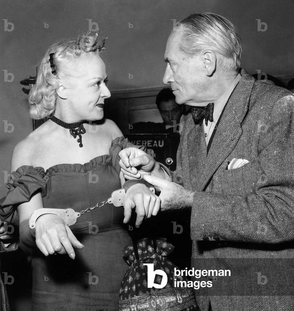 French Writer and Scriptwriter Maurice Dekobra Hancuffs Actress Fanny Mauve (Wife of Fench Deputy) on Set of Film La Rafle Est Pour Ce Soir Ecrit November, 20 1953 (b/w photo)