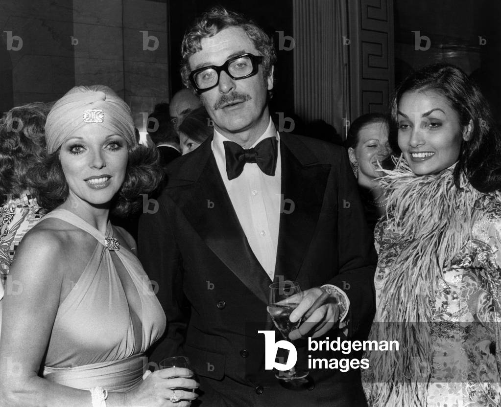 Joan Collins (L) and English Actor Michael Caine and his Wife Shakira on September 12, 1974 (b/w photo)