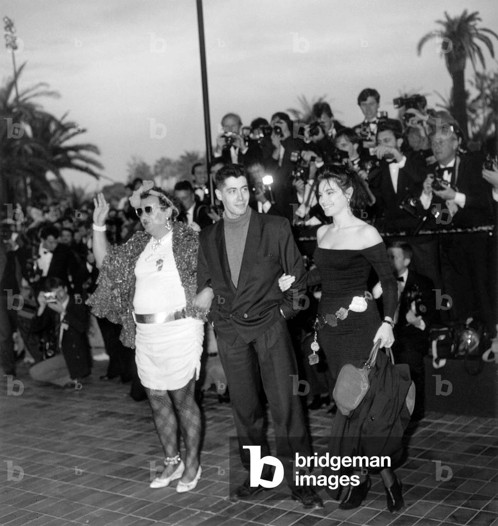 French Actor Coluche Dressed As A Woman Transvestite Arriving With Actress Beatrice Dalle and Husband at Cannes Film Festival Besieged By Photographers (b/w photo)
