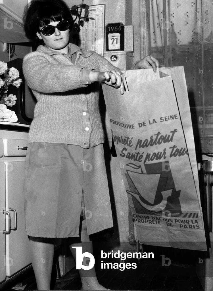 A Menagere Showing Her Garbage Bag Disribue By The Parisian Town Council Following Les Greves Generaliss And The Total Stop Of 4000 Parisian Slanders May 22, 1968 (b/w photo)
