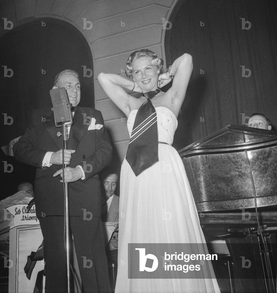 The Night of the shirt trade in Paris (Claridge's), May 10, 1950 : a young woman presenting ties, helped by French singer Saint Granier (b/w photo)