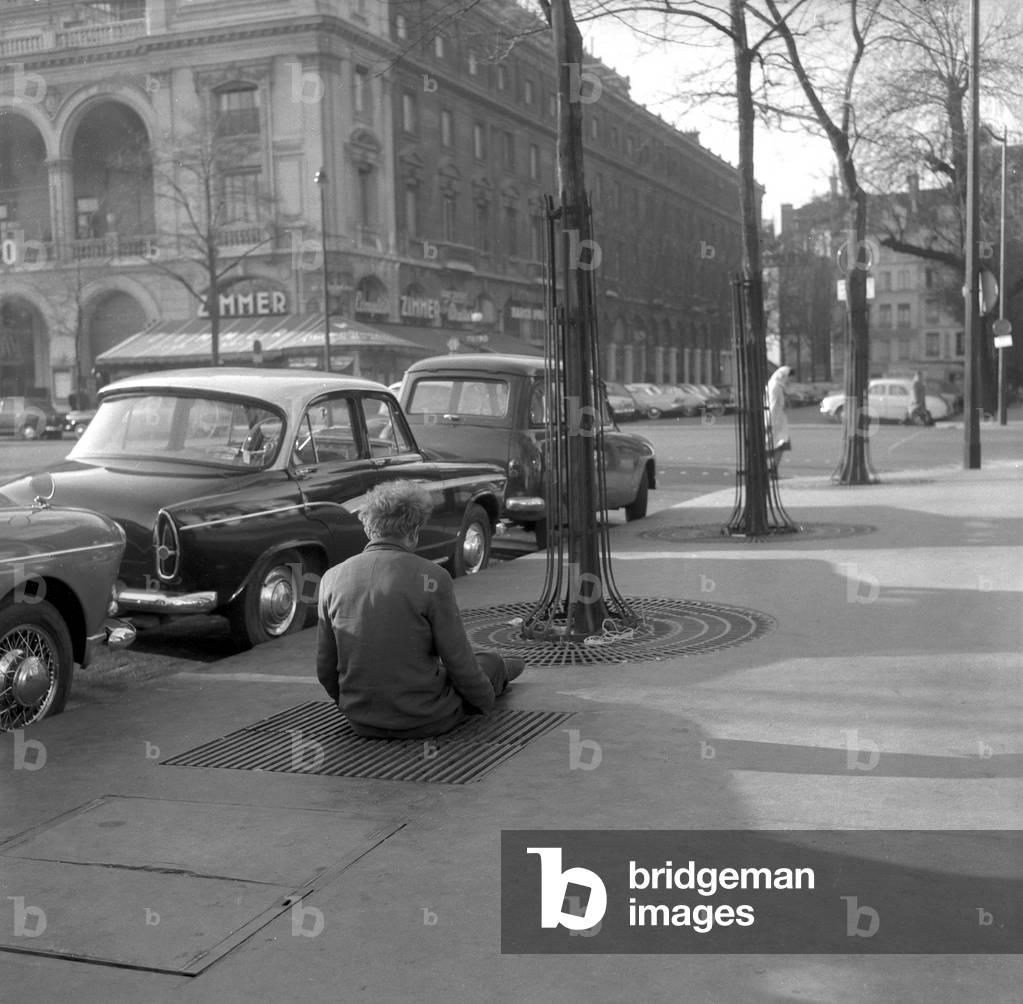 Winter 1960 in Paris : A Homeless Is Sitting on A Grate Over The Subway Trying To Warm Himself Up, January 10, 1960 (b/w photo)